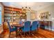 Formal dining room with hardwood floors, built-in bookcase, chandelier, and comfortable blue chairs at 3227 Morrow Farm Ln, Chapel Hill, NC 27516