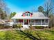 Charming red home with a metal roof, a wraparound porch, and lush landscaping at 3227 Morrow Farm Ln, Chapel Hill, NC 27516