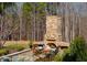 Stone outdoor fireplace with seating area and lush landscaping perfect for outdoor entertaining and relaxation at 3227 Morrow Farm Ln, Chapel Hill, NC 27516