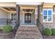 Inviting front porch showcasing a brick staircase, dark stained columns, and an elegant, double-door entrance at 3240 Donlin Dr, Wake Forest, NC 27587