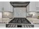 Close-up of a stainless steel range with stylish tile backsplash and custom range hood at 3240 Donlin Dr, Wake Forest, NC 27587
