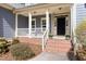 Close up of the front porch with brick steps, white railings, and a welcoming entrance with potted flowers at 3541 Rugby Rd, Durham, NC 27707