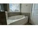 Bright soaking tub with tile surround and window with sunlight streaming in at 49 W Copenhaver Dr, Clayton, NC 27527