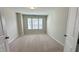 Large bedroom with neutral carpet, three windows, and a door leading to the hall at 49 W Copenhaver Dr, Clayton, NC 27527