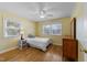 Sun-filled bedroom featuring hardwood floors, two windows, and light yellow striped wallpaper at 5108 Melbourne Rd, Raleigh, NC 27606