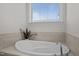 Close up of soaking tub with tile surround and a garden window providing natural light at 517 Aronia Dr, Hillsborough, NC 27278