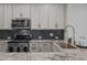 Well-equipped kitchen with white cabinets, stainless steel appliances, and stylish dark backsplash at 517 Aronia Dr, Hillsborough, NC 27278
