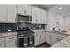 Modern kitchen featuring white cabinets, stainless steel appliances, granite countertops, and dark backsplash tiles at 517 Aronia Dr, Hillsborough, NC 27278
