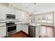 Bright kitchen boasts granite countertops, stainless steel appliances, white cabinetry, and pendant lighting at 525 Fallon Grove Way, Raleigh, NC 27608