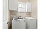 Bright laundry room with white washer and dryer, storage cabinets, and a window at 525 Fallon Grove Way, Raleigh, NC 27608