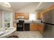 Well-lit kitchen with wooden cabinets, granite countertops, black appliances, and a stainless steel refrigerator at 5513 Edgebury Rd, Raleigh, NC 27613