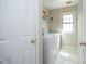 Bright laundry room with a white washer and dryer, storage shelves, and a window for natural light at 5513 Edgebury Rd, Raleigh, NC 27613