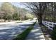 Tree-lined street with a sidewalk and white picket fence, creating a picturesque and inviting neighborhood scene at 5513 Edgebury Rd, Raleigh, NC 27613