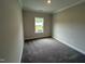 Neutral-toned bedroom featuring plush carpeting, a window providing natural light, and clean, bright white trim at 712 Swim Cave Ln, Wendell, NC 27591