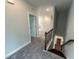 Hallway with carpeted floors, showcasing an open doorway and staircase with wooden railing at 712 Swim Cave Ln, Wendell, NC 27591