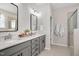 Bathroom featuring dual sinks, gray vanity with black hardware, framed mirrors and a glass enclosed shower at 724 Summer Music Ln, Raleigh, NC 27603