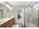 Bright bathroom showcasing a double sink vanity, glass shower enclosure, and an open doorway to the bedroom at 73 Vibernum Vw, Four Oaks, NC 27524