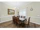 Dining room with wood floors, decorative framed art, six chairs and a wooden table with a white table runner at 73 Vibernum Vw, Four Oaks, NC 27524
