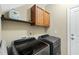 Well-lit laundry room showcasing modern washer and dryer with overhead cabinets and a convenient shelf at 73 Vibernum Vw, Four Oaks, NC 27524