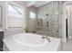 Bathroom with a large soaking tub, glass shower, and gray tiled walls at 832 Mountain Vista Ln, Cary, NC 27519
