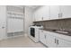 Laundry room featuring white cabinets, utility sink, washer, dryer and tile floors at 832 Mountain Vista Ln, Cary, NC 27519