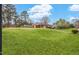 Lush green lawn and mature trees surround this cozy single-story home, with a long covered porch, under a blue sky at 902 Long Ave, Garner, NC 27529