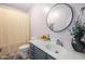 Well-lit bathroom with a vanity, round mirror, and shower with a patterned curtain at 992 Ambergate, Apex, NC 27502