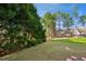 A backyard with a large grassy lawn with a view of other homes beyond trees at 101 Whitney Ln, Durham, NC 27713