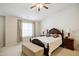 Bright main bedroom with a ceiling fan, beige carpet, a dark wood bedframe, and ensuite bathroom access at 101 Whitney Ln, Durham, NC 27713