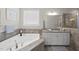 Relaxing bathroom featuring a soaking tub with tile surround, granite counters, and a window for natural light at 1212 Stonemill Falls Dr, Wake Forest, NC 27587