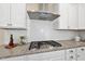 Close-up view of the kitchen showcasing the gas range, range hood, and granite countertops at 1212 Stonemill Falls Dr, Wake Forest, NC 27587