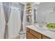 Neutral bathroom with white shower curtain, wood vanity, framed mirror, and decorative shelving at 123 Carbone Ln, Clayton, NC 27527
