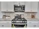 Close up of stainless steel gas range and microwave paired with white cabinetry and granite countertops at 123 Carbone Ln, Clayton, NC 27527