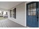 Charming porch featuring a blue front door, window with black shutters, and gray painted wooden boards at 1304 Drew St, Durham, NC 27701