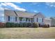 View of a single-story house featuring gray siding, black shutters, well-maintained landscaping, and an attached two-car garage at 131 Woodglen Dr, Clayton, NC 27527