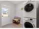 Bright laundry room featuring a stacked washer and dryer, tiled floors, and a convenient bench at 1312 Big Falls Dr, Wendell, NC 27591