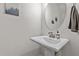 Bright powder room featuring a pedestal sink with modern faucet and oval mirror at 175 Norwell Ln, Pittsboro, NC 27312