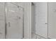 Modern walk-in shower with marble-look tile and a glass door is next to an open doorway at 175 Norwell Ln, Pittsboro, NC 27312