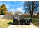 View of the backyard with a wooden fence, two trees, and a covered outdoor cooking area at 1930 Maple Sugar Ln, Fuquay Varina, NC 27526