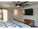 Bedroom featuring hardwood floors, a large TV, ceiling fan, and a barn door to the bathroom at 1930 Maple Sugar Ln, Fuquay Varina, NC 27526