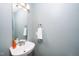 Close-up of a half bathroom with a pedestal sink, a large mirror, and a towel ring on a pale blue wall at 209 Tullich Way, Holly Springs, NC 27540