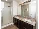 Bathroom with double vanity, granite countertop, framed mirror, and glass shower at 209 Tullich Way, Holly Springs, NC 27540