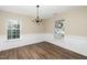 Spacious dining room with wainscoting, wood flooring, and a chandelier, illuminated by natural light from two large windows at 209 Tullich Way, Holly Springs, NC 27540