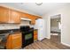 Efficient kitchen featuring light wood cabinets, black appliances, granite countertops, and stylish wood-look flooring at 209 Tullich Way, Holly Springs, NC 27540