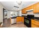 Spacious kitchen featuring light wood cabinetry, black countertops, stainless steel dishwasher, and durable wood-look flooring at 209 Tullich Way, Holly Springs, NC 27540