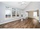Bright living room features large windows, white-painted brick, wood flooring, and an open doorway to the kitchen at 209 Tullich Way, Holly Springs, NC 27540