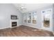 Living room featuring a fireplace with a white mantle, large windows providing natural light, and a glass door at 209 Tullich Way, Holly Springs, NC 27540