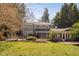 Back of home featuring a well-maintained yard, large screened-in porch, and lush landscaping at 212 W University Dr, Chapel Hill, NC 27516
