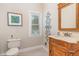 Bathroom features a decorative wood vanity, framed mirror, artwork, and neutral tiling at 2601 Forestville Rd, Wake Forest, NC 27587