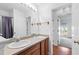 Bathroom featuring double sinks, wood cabinetry, and an expansive mirror, with a glimpse into another room at 2776 Jordan Ct, Creedmoor, NC 27522
